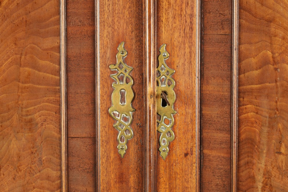 A George III mahogany hanging clothes press featuring two flame mahogany panelled doors over four drawers with brass handles, raised on bracket feet. View III