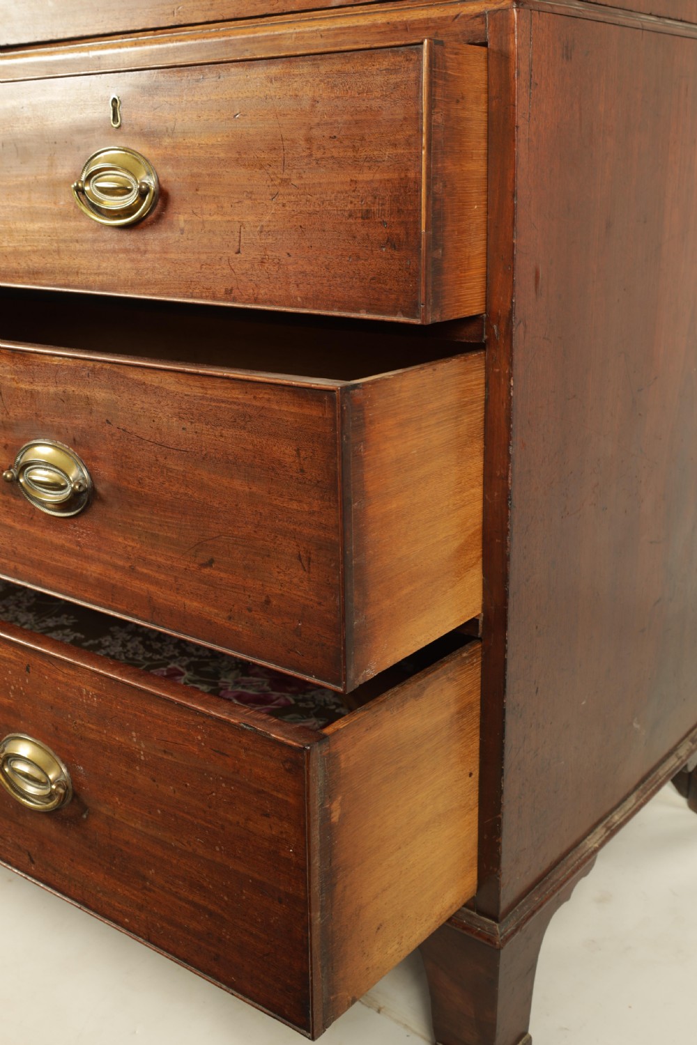 A George III mahogany hanging clothes press featuring two flame mahogany panelled doors over four drawers with brass handles, raised on bracket feet. View V