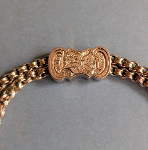 fig 3. An antique 9ct gold double chain bracelet featuring engraved heart-shaped end pieces, a swivel clasp, and a hanging gold tassel charm.
