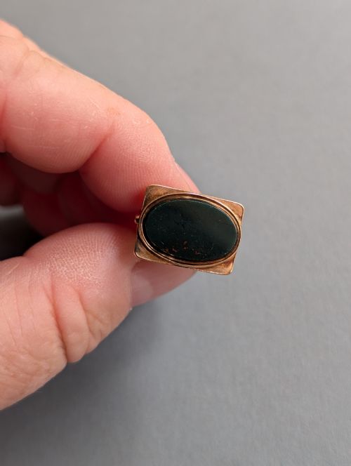 fig 2. An Edwardian 9ct gold watch fob featuring an arched cage superstructure, geometric chased detailing around the frame, and a dark green bloodstone seal base.