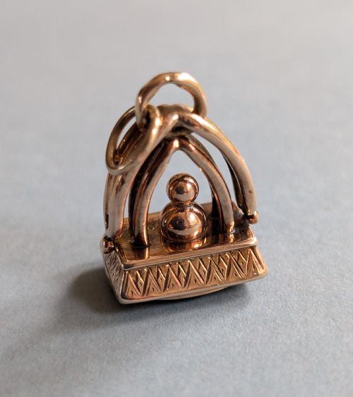 fig 3. An Edwardian 9ct gold watch fob featuring an arched cage superstructure, geometric chased detailing around the frame, and a dark green bloodstone seal base.