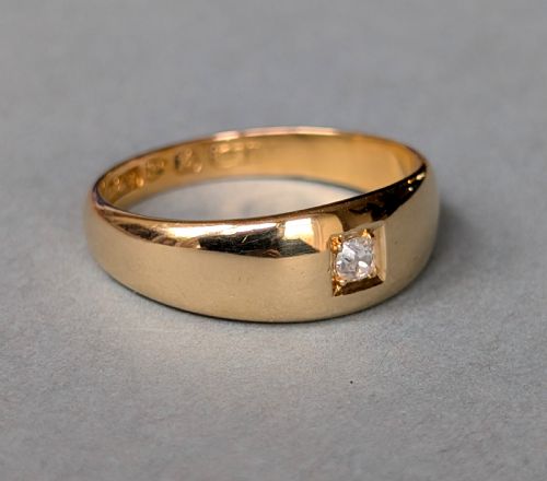 fig 1. An antique 15ct yellow gold band ring featuring a single flush-set diamond and internal British hallmarks.