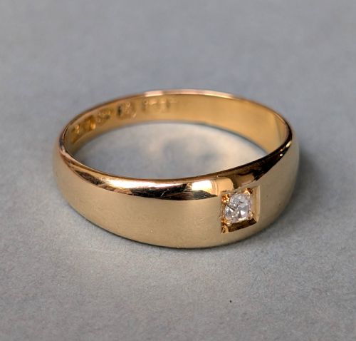 fig 2. An antique 15ct yellow gold band ring featuring a single flush-set diamond and internal British hallmarks.