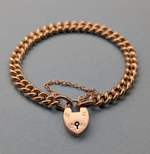 fig 1. An antique 9ct rose gold curb chain bracelet featuring a heart-shaped padlock clasp and an attached safety chain.