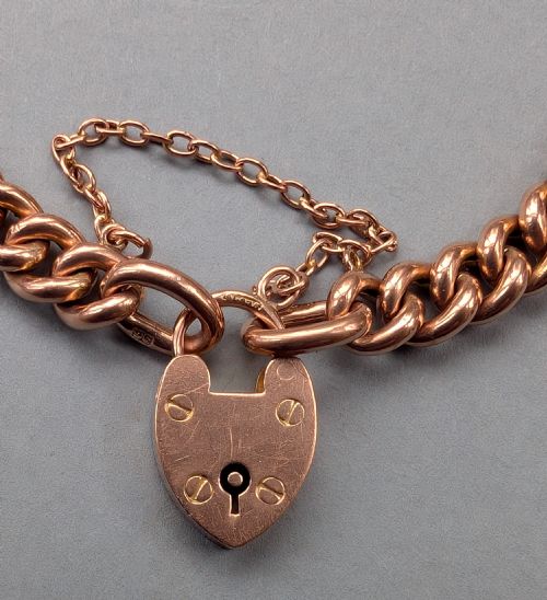 fig 3. An antique 9ct rose gold curb chain bracelet featuring a heart-shaped padlock clasp and an attached safety chain.