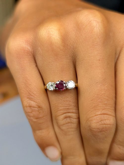 fig 1. An 18ct gold trilogy ring featuring a round central red ruby flanked by two diamonds in claw settings.