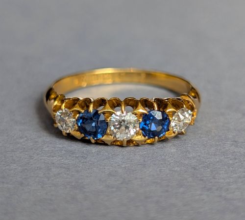 fig 1. An Edwardian 18ct yellow gold five-stone ring featuring alternating blue sapphires and old cut diamonds set within a carved scroll head.