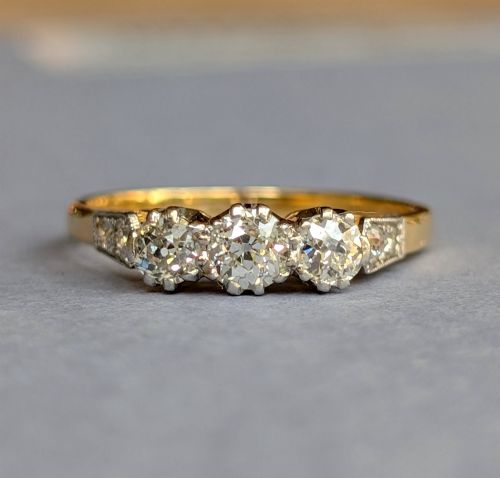 fig 1. An 18ct yellow gold Art Deco ring featuring three round diamonds set horizontally with platinum-mounted diamond accents on the shoulders.