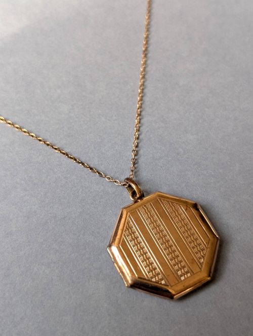 fig 1. An octagonal 9ct rose gold locket featuring engine-turned geometric engraving suspended from a fine gold chain.