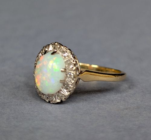 fig 2. A mid-century 18ct gold ring featuring an oval cabochon opal framed by a halo cluster of small diamonds.