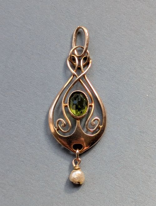 fig 1. An Edwardian 9ct gold openwork Art Nouveau pendant featuring an oval bezel-set green peridot and a suspended pearl drop.