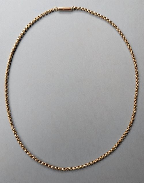 fig 2. An antique 9ct yellow gold belcher chain laid on a plain background showing interlocking rounded links and a barrel fastener.