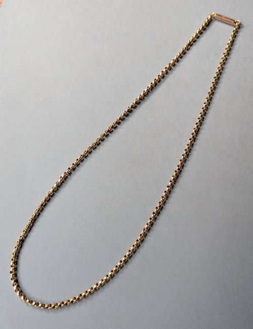 fig 3. An antique 9ct yellow gold belcher chain laid on a plain background showing interlocking rounded links and a barrel fastener.