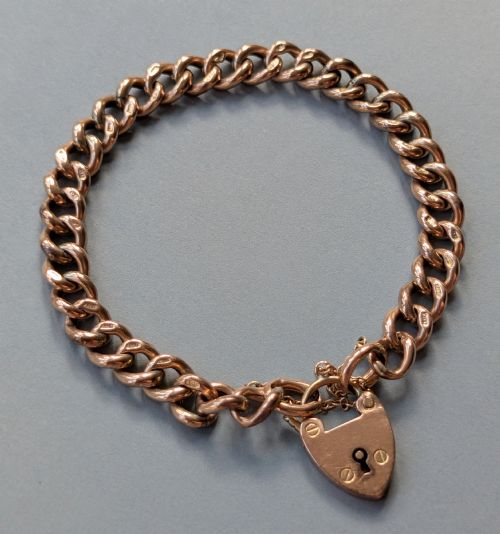 fig 1. An Edwardian 9ct rose gold curb link chain bracelet featuring a heart-shaped padlock clasp and safety chain.