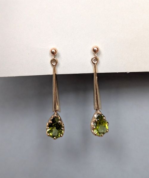 fig 2. A pair of antique 9ct gold drop earrings featuring tapered bars and pear-cut green peridot gemstones suspended from ball posts.
