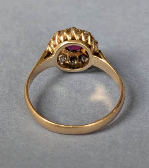 fig 3. An antique 18ct gold cluster ring featuring a central faceted red ruby surrounded by ten round diamonds.