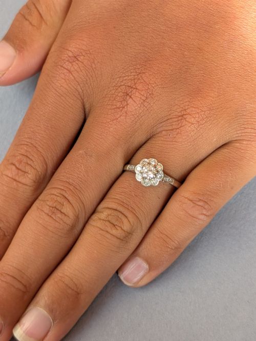 fig 1. An Art Deco diamond cluster ring featuring a flower motif halo setting on a slender metallic band.