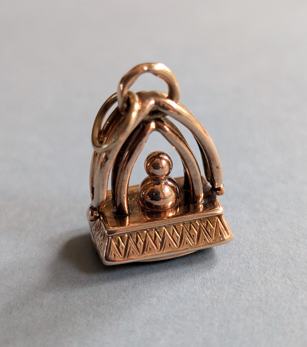 An Edwardian 9ct gold watch fob featuring an arched cage superstructure, geometric chased detailing around the frame, and a dark green bloodstone seal base. View IV