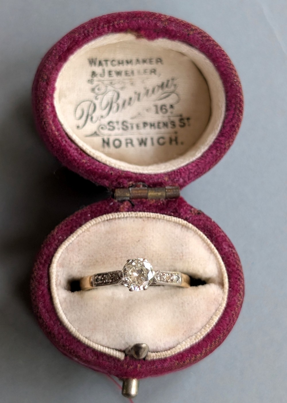 An Art Deco diamond solitaire engagement ring featuring a central round diamond set in platinum claws with diamond-accented shoulders on a yellow gold band. View IX