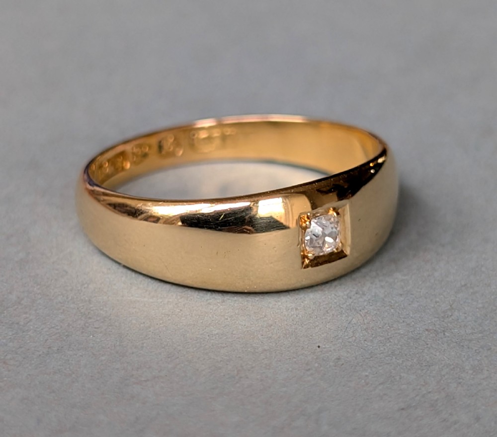 An antique 15ct yellow gold band ring featuring a single flush-set diamond and internal British hallmarks. View II