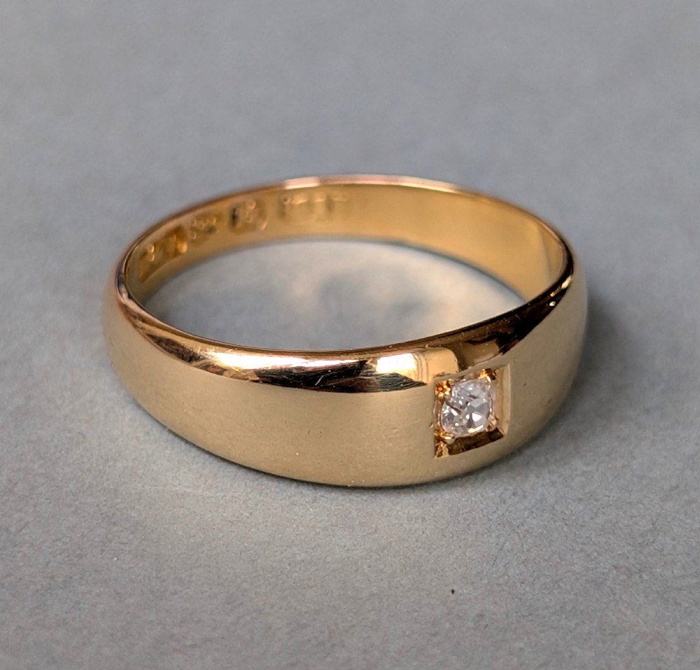 An antique 15ct yellow gold band ring featuring a single flush-set diamond and internal British hallmarks. View III