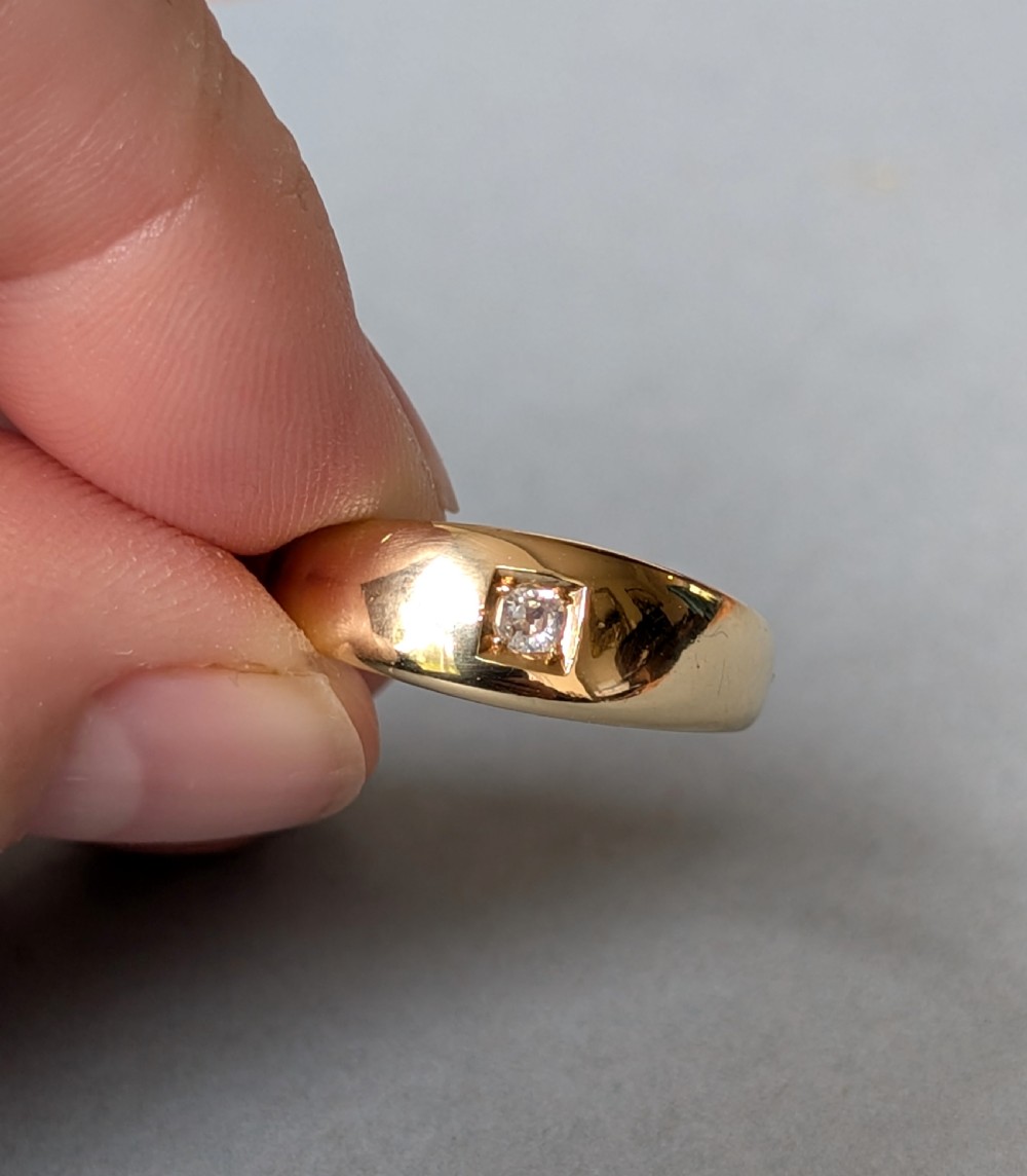 An antique 15ct yellow gold band ring featuring a single flush-set diamond and internal British hallmarks. View IV