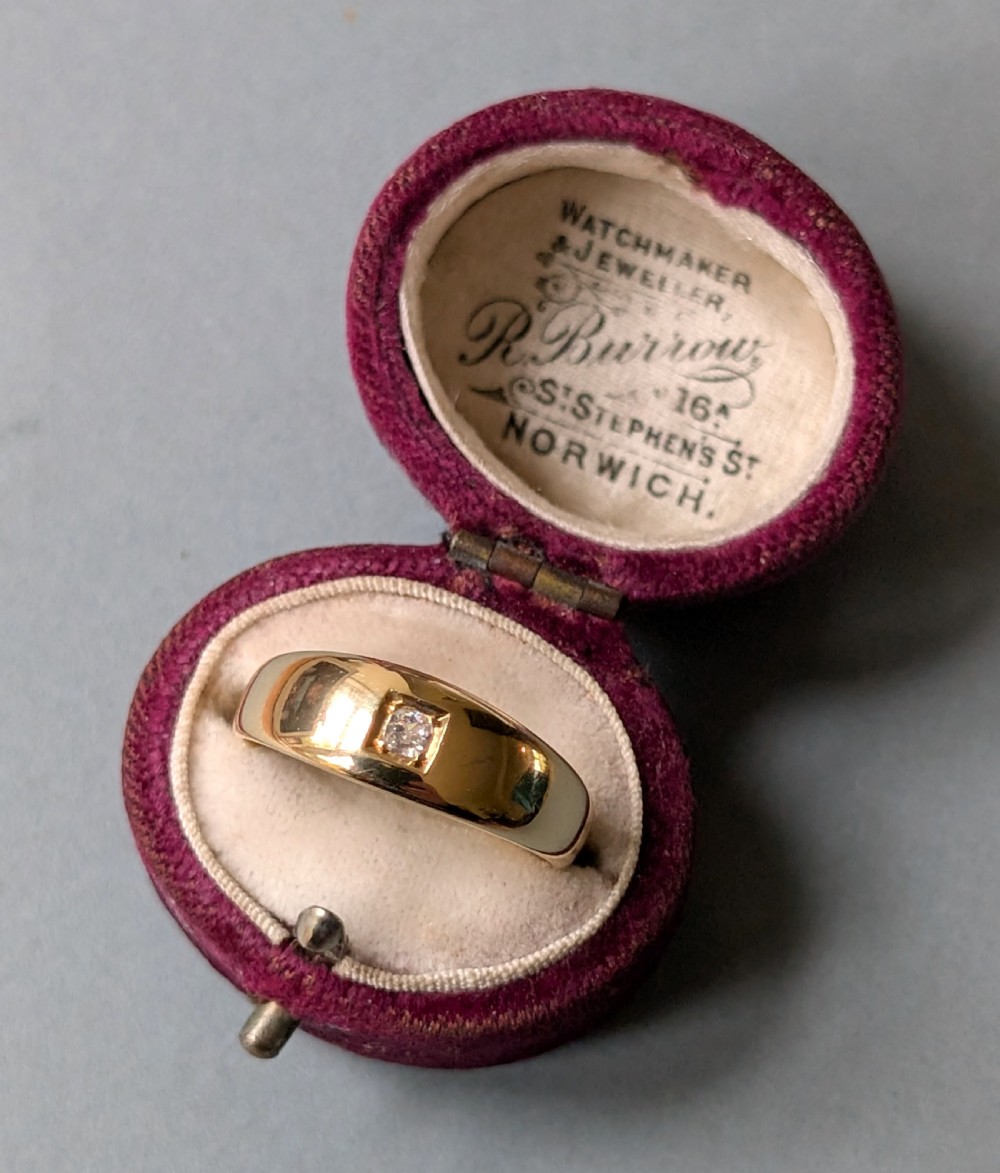 An antique 15ct yellow gold band ring featuring a single flush-set diamond and internal British hallmarks. View VIII
