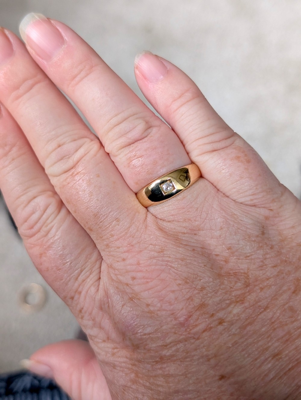 An antique 15ct yellow gold band ring featuring a single flush-set diamond and internal British hallmarks. View IX