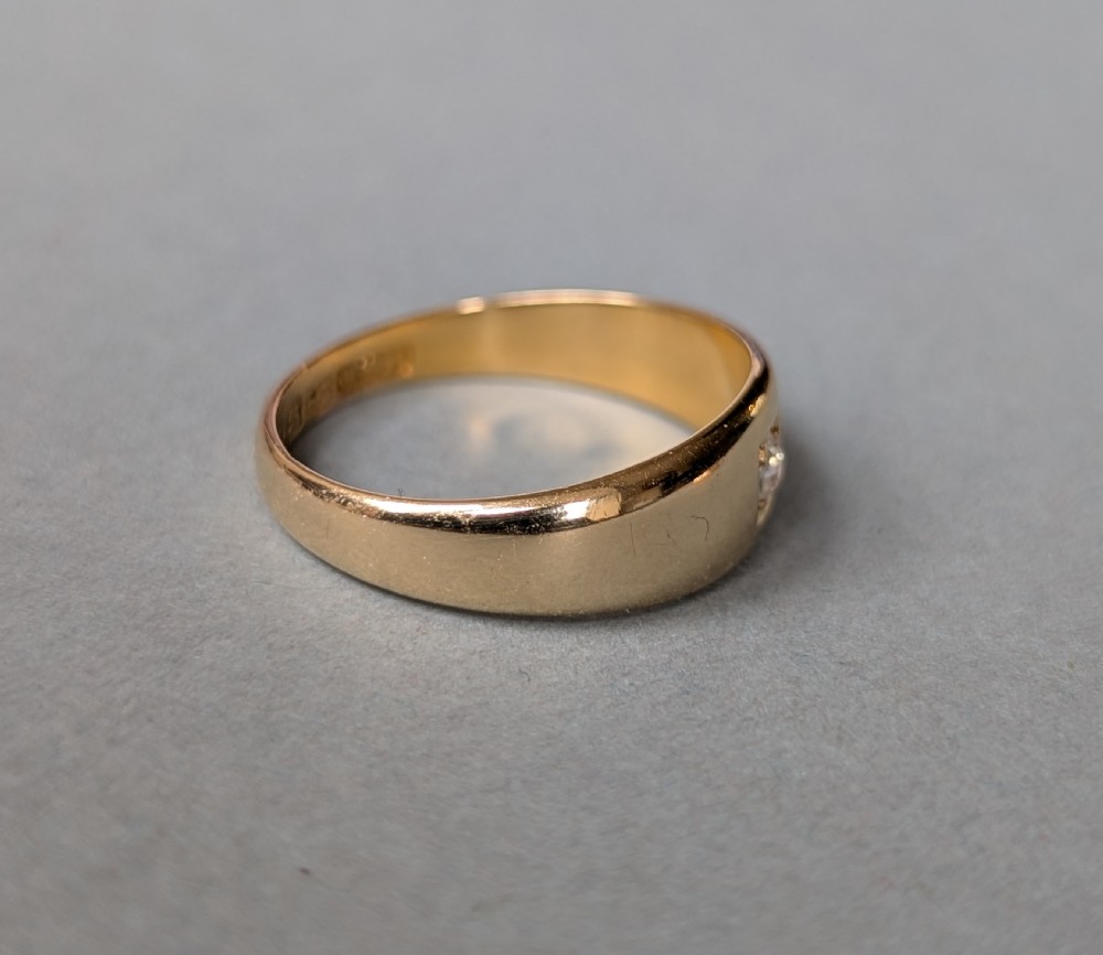 An antique 15ct yellow gold band ring featuring a single flush-set diamond and internal British hallmarks. View X