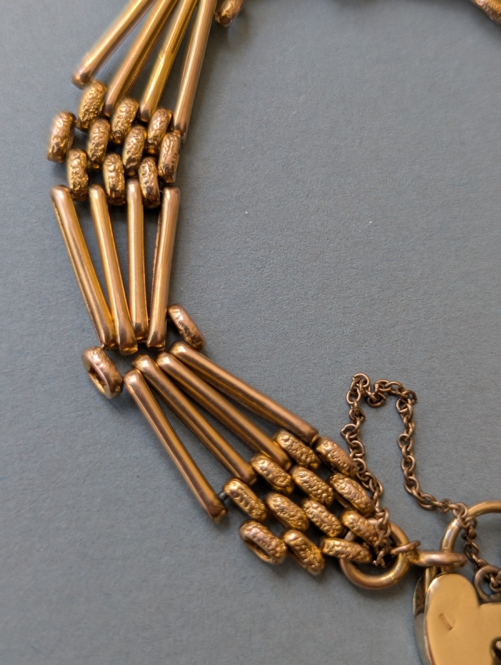 An antique 9ct yellow gold gate link bracelet featuring textured link accents, a safety chain, and a heart-shaped padlock clasp. View II