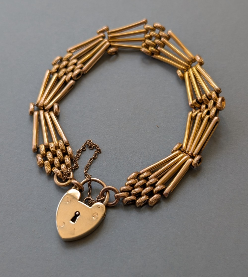 An antique 9ct yellow gold gate link bracelet featuring textured link accents, a safety chain, and a heart-shaped padlock clasp. View V