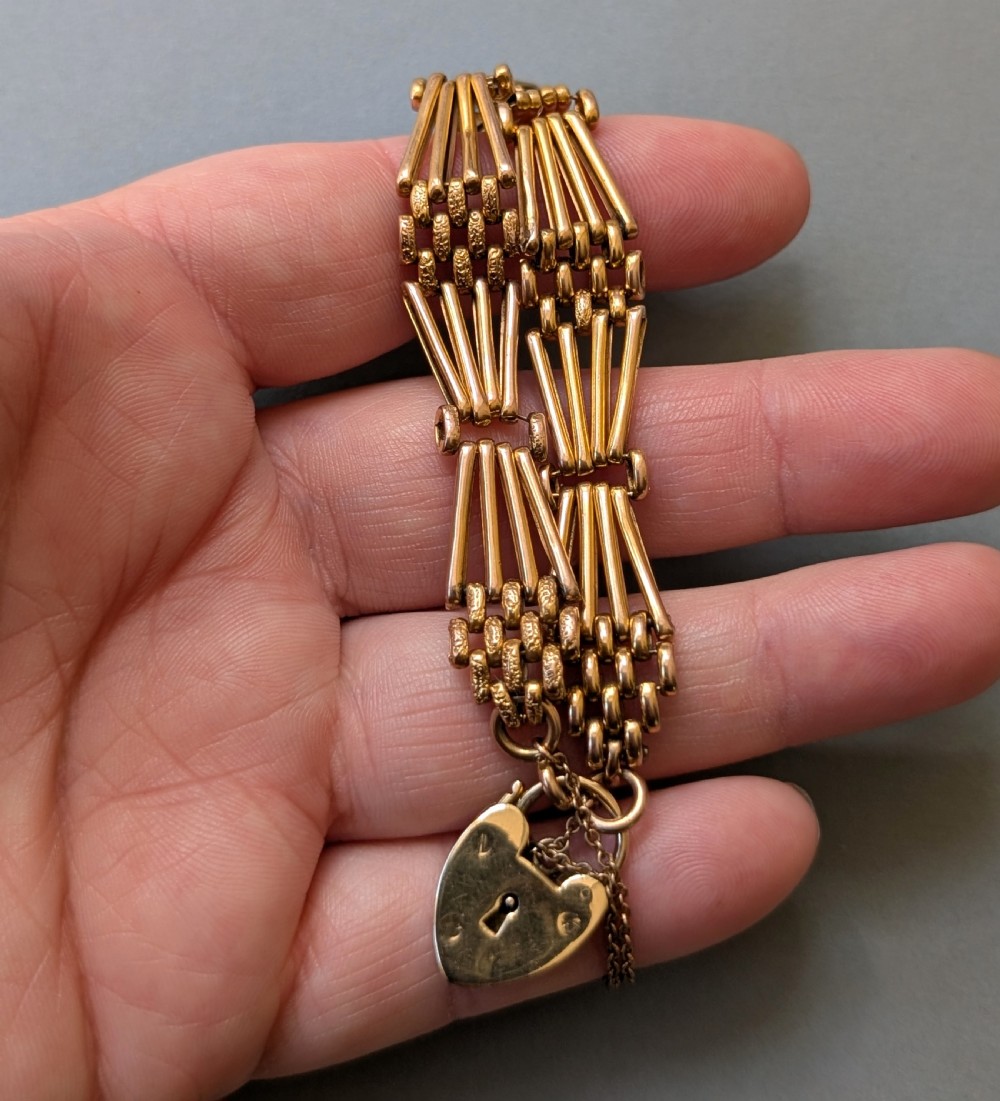 An antique 9ct yellow gold gate link bracelet featuring textured link accents, a safety chain, and a heart-shaped padlock clasp. View IX
