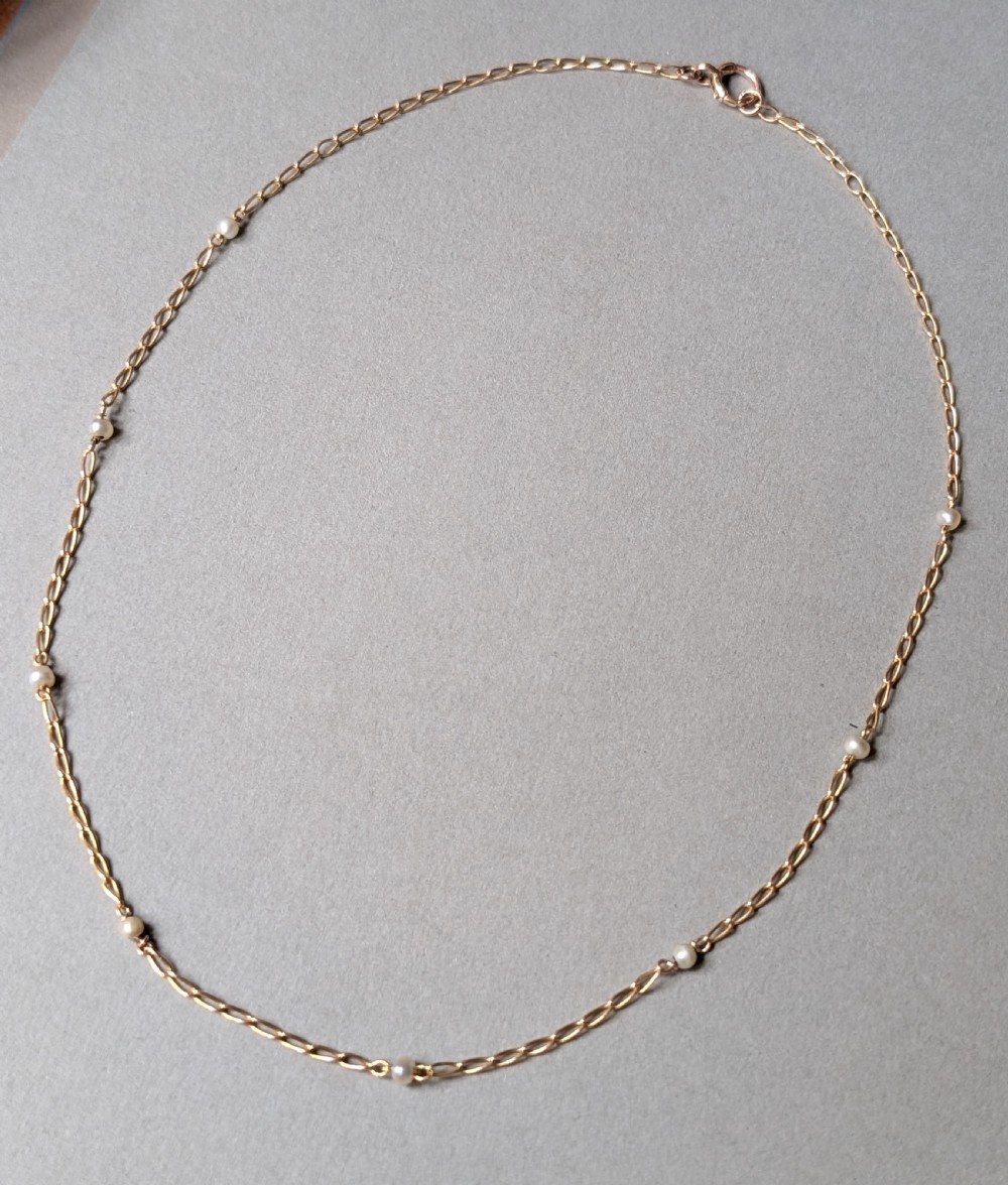 A fine 9ct yellow gold link chain accented with small round pearls placed at spaced intervals. View V