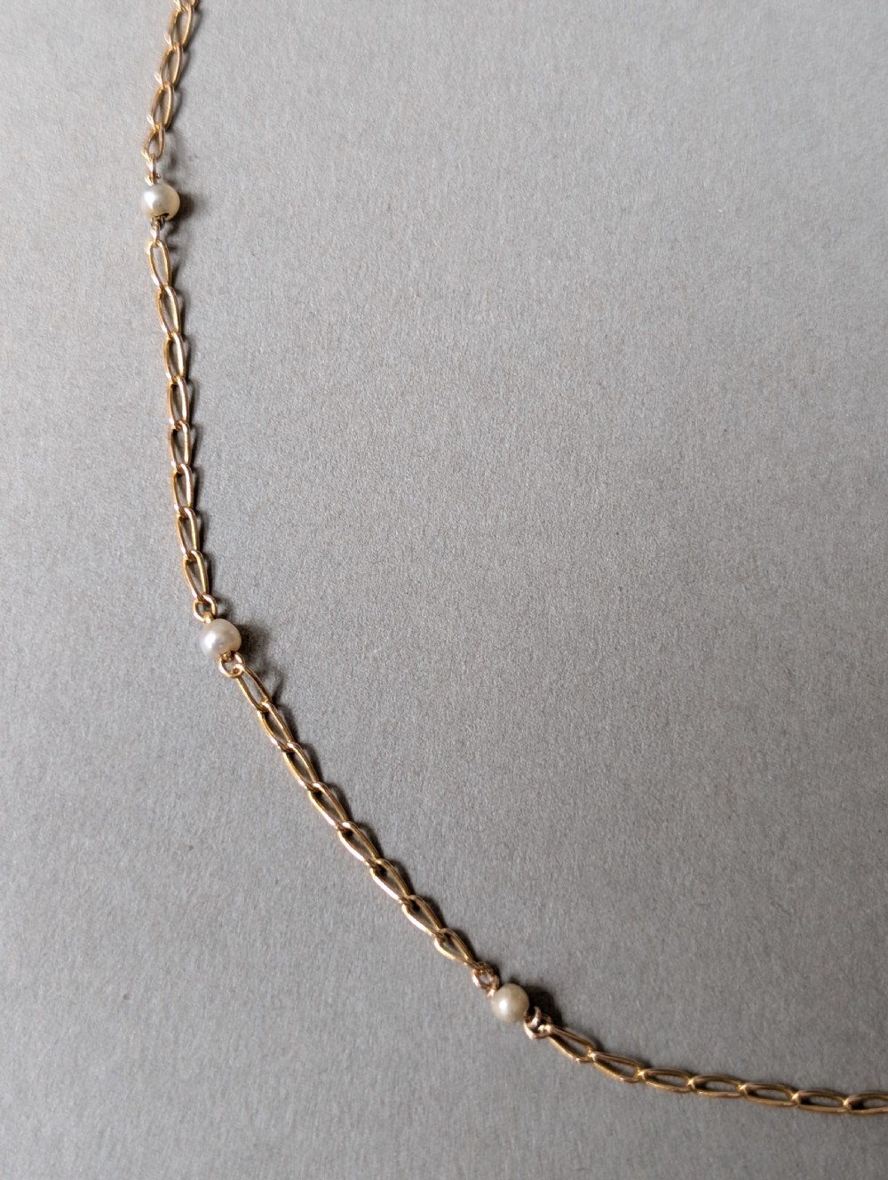 A fine 9ct yellow gold link chain accented with small round pearls placed at spaced intervals. View VI
