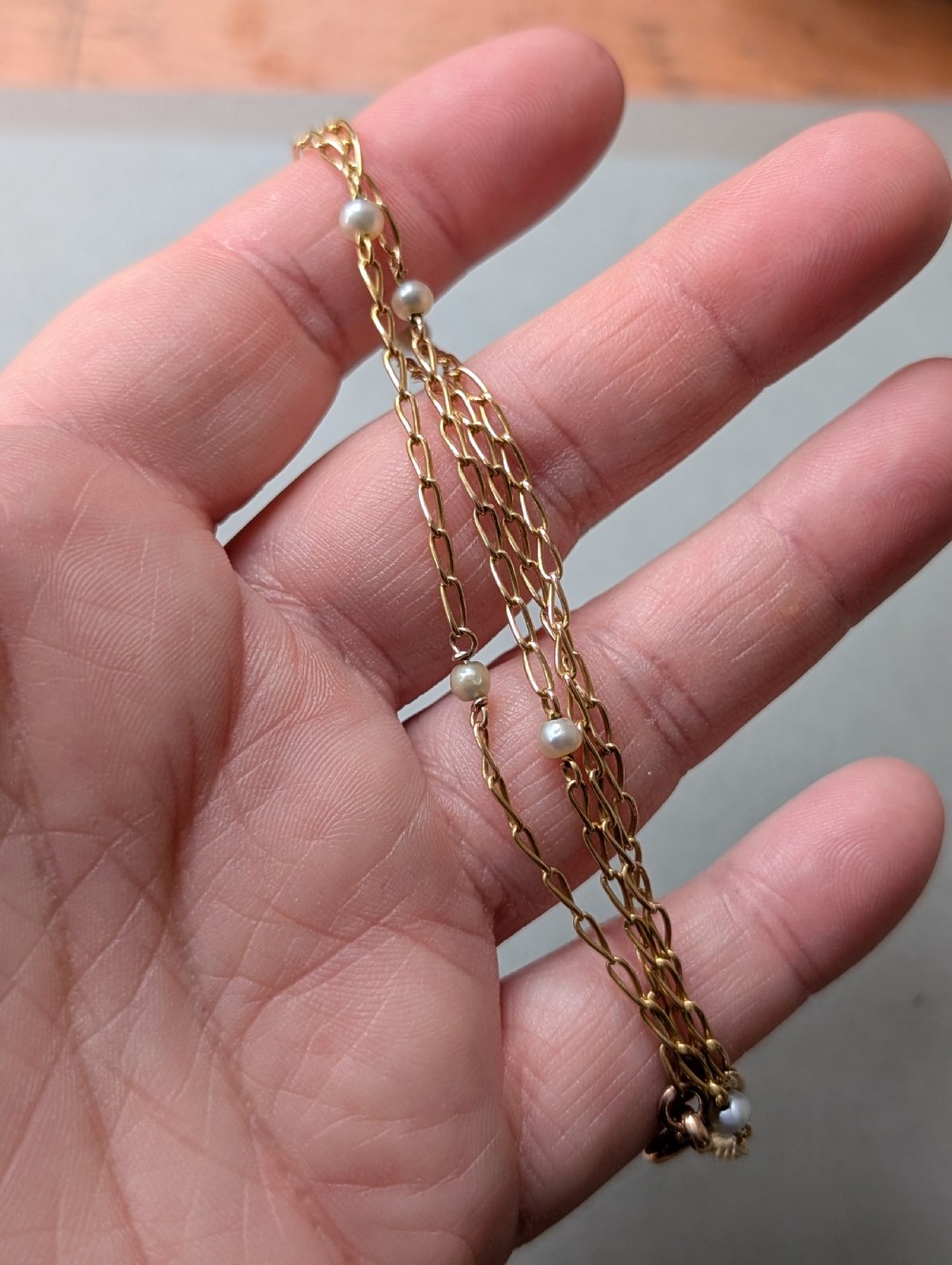 A fine 9ct yellow gold link chain accented with small round pearls placed at spaced intervals. View IX