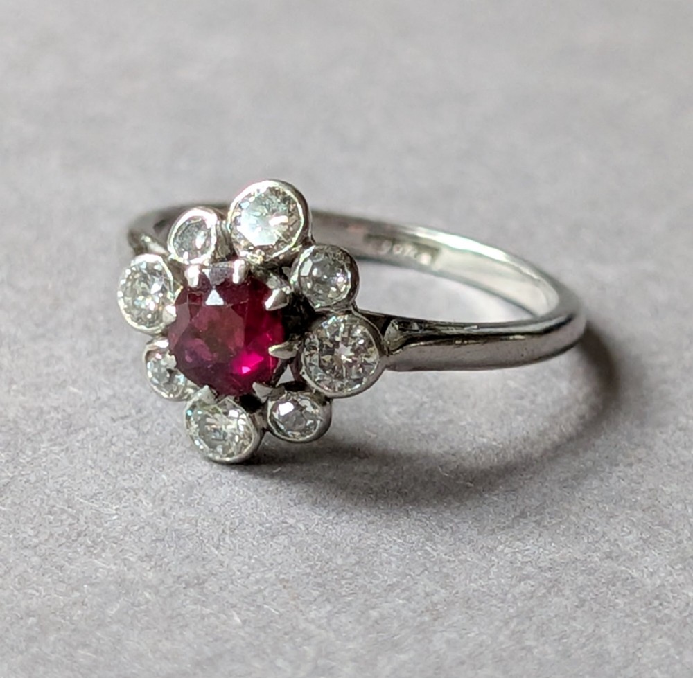 An Art Deco platinum ring featuring a circular central red ruby surrounded by a cluster halo of eight round diamonds. View VIII