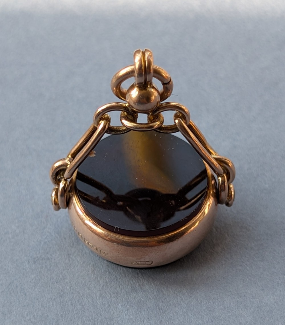 An Edwardian 9ct gold spinning fob pendant set with a polished circular dark green bloodstone gemstone with red flecks. View II