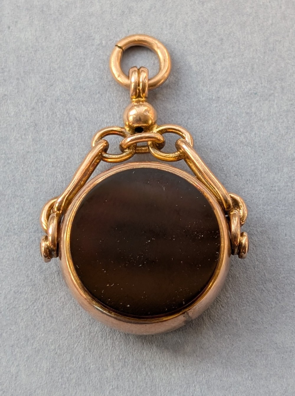 An Edwardian 9ct gold spinning fob pendant set with a polished circular dark green bloodstone gemstone with red flecks. View IV