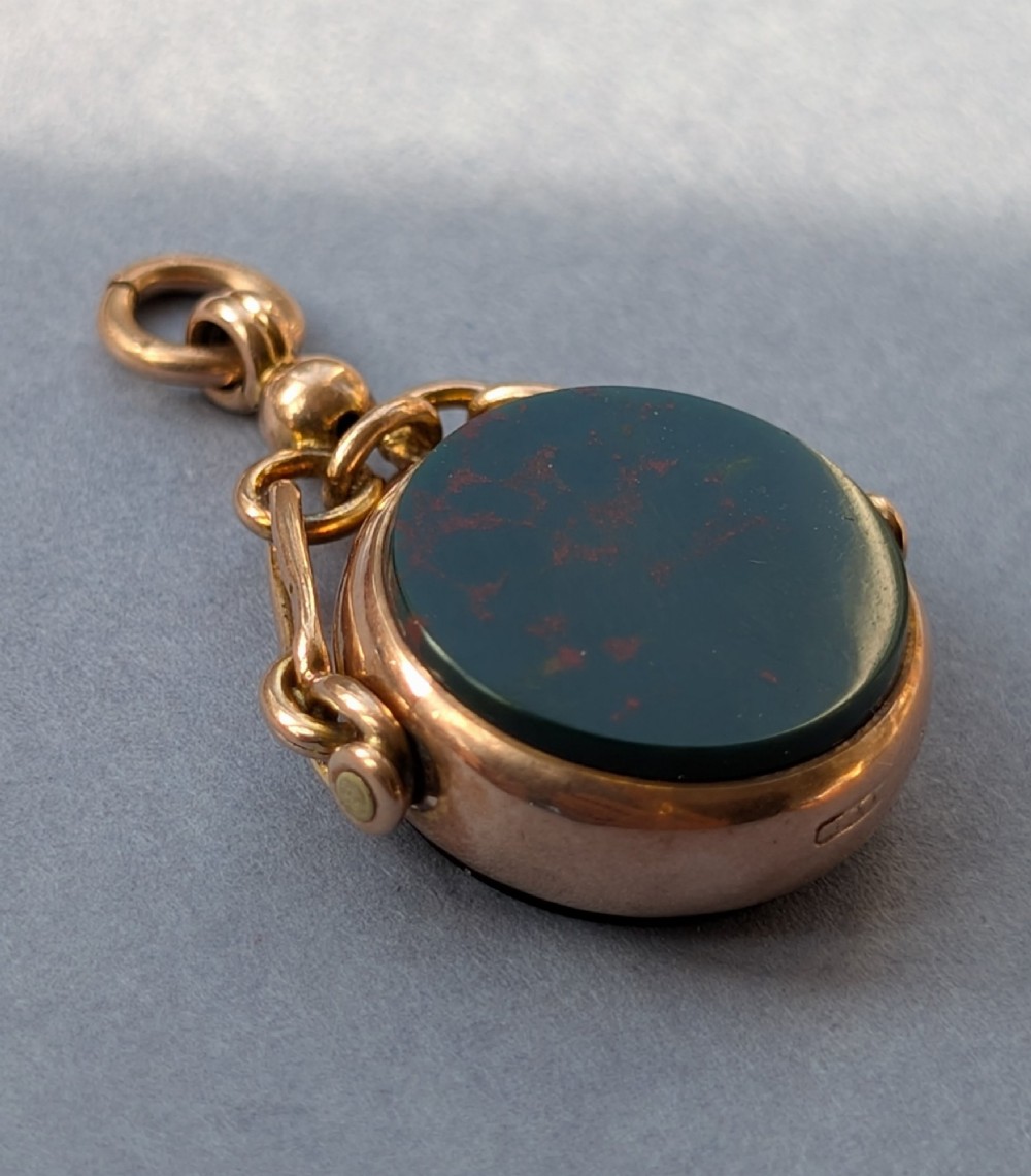 An Edwardian 9ct gold spinning fob pendant set with a polished circular dark green bloodstone gemstone with red flecks. View V