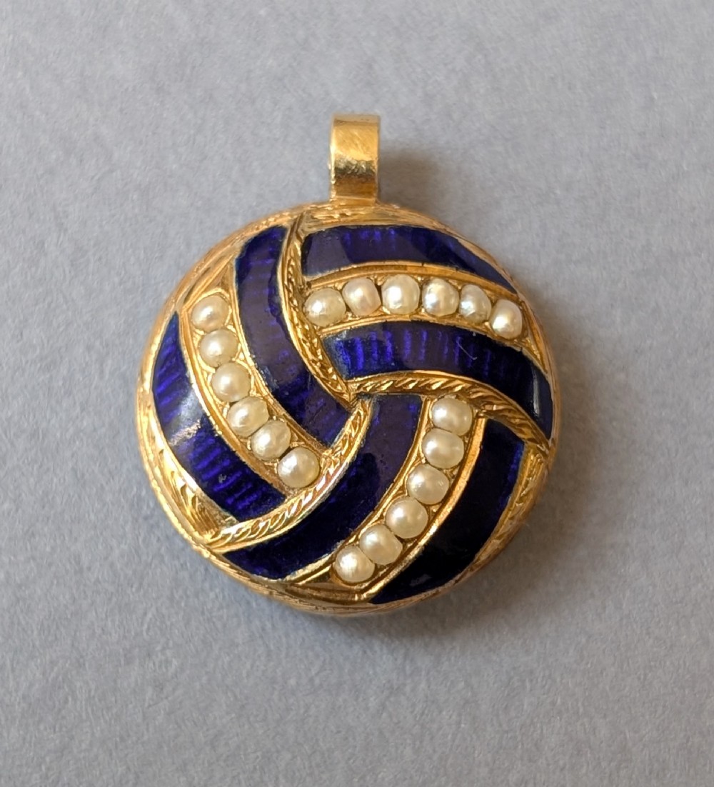 A circular Victorian gold pendant featuring spiralling bands of cobalt blue enamel and set split pearls.