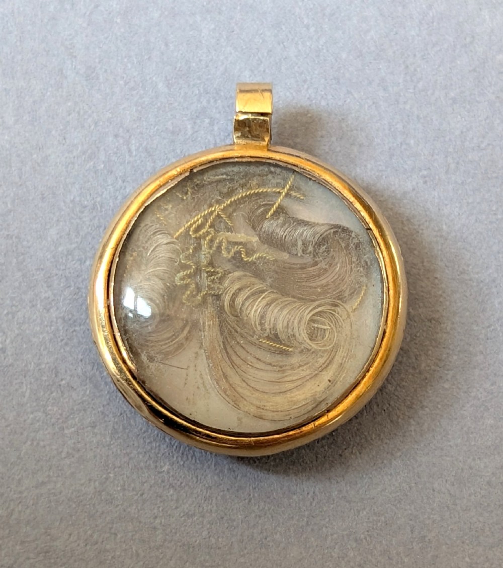 A circular Victorian gold pendant featuring spiralling bands of cobalt blue enamel and set split pearls. View VI