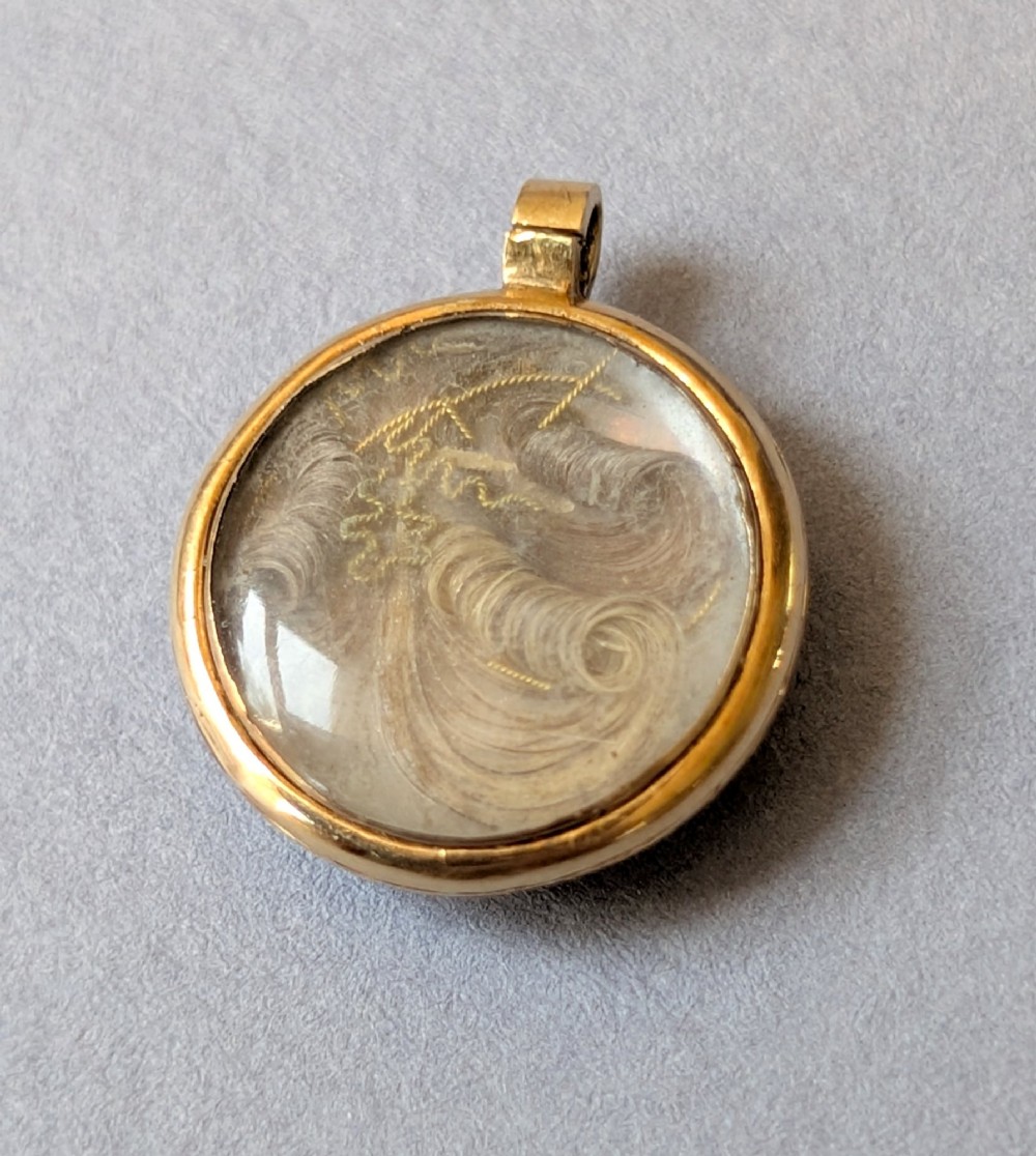 A circular Victorian gold pendant featuring spiralling bands of cobalt blue enamel and set split pearls. View VII