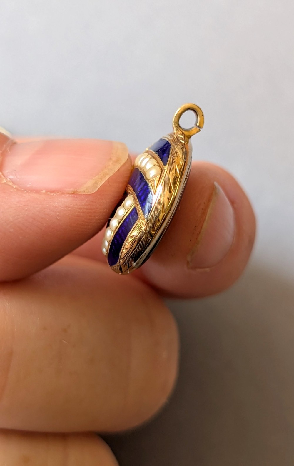 A circular Victorian gold pendant featuring spiralling bands of cobalt blue enamel and set split pearls. View IX