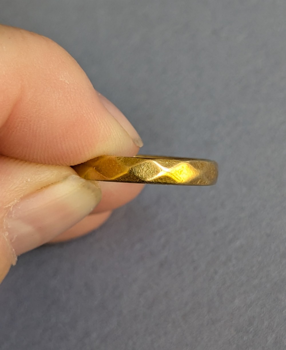 A vintage 18ct yellow gold wedding band featuring a faceted geometric pattern around the exterior surface. View III