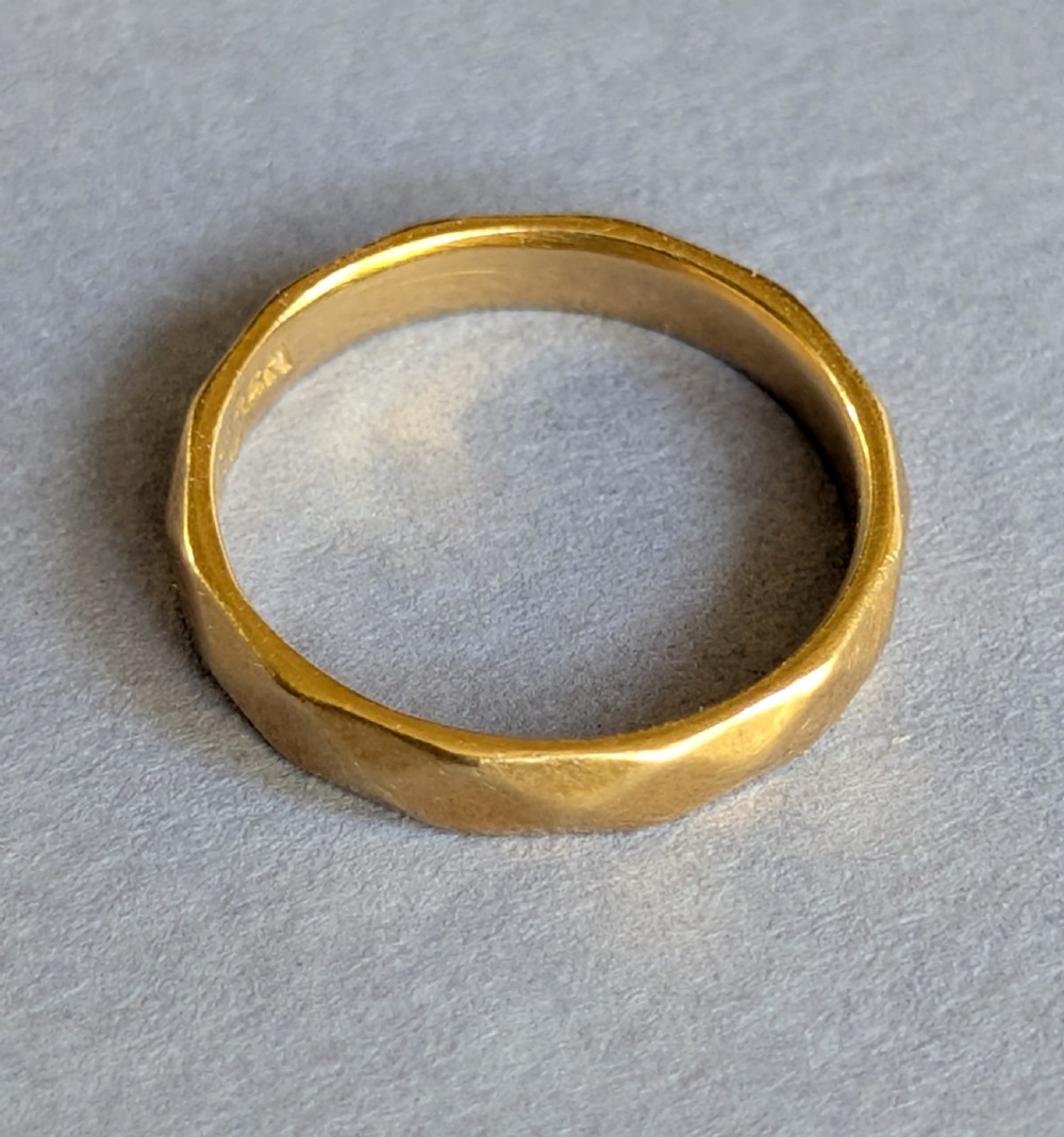 A vintage 18ct yellow gold wedding band featuring a faceted geometric pattern around the exterior surface. View IV