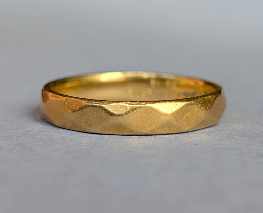 A vintage 18ct yellow gold wedding band featuring a faceted geometric pattern around the exterior surface. View V