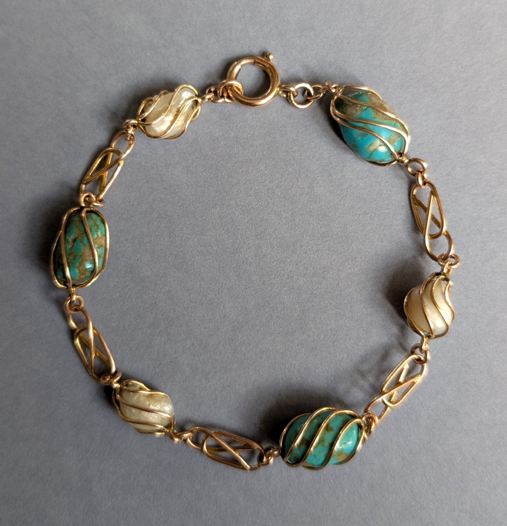 An antique 9ct rose gold bracelet featuring alternating wire-caged turquoise and pearl beads connected by openwork links with a bolt ring clasp. View IV