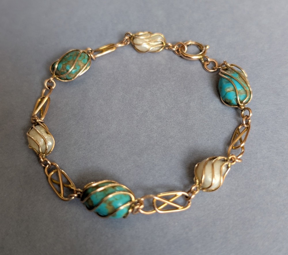 An antique 9ct rose gold bracelet featuring alternating wire-caged turquoise and pearl beads connected by openwork links with a bolt ring clasp. View V