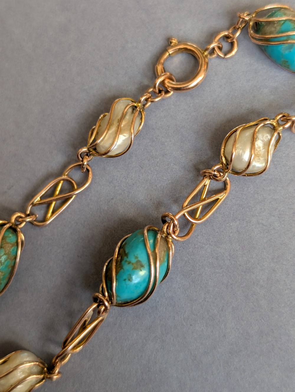 An antique 9ct rose gold bracelet featuring alternating wire-caged turquoise and pearl beads connected by openwork links with a bolt ring clasp. View VII