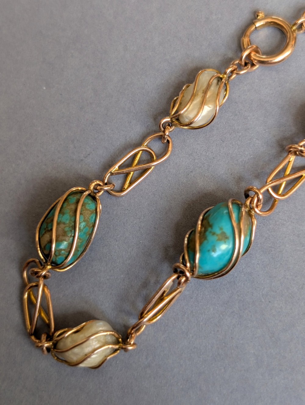 An antique 9ct rose gold bracelet featuring alternating wire-caged turquoise and pearl beads connected by openwork links with a bolt ring clasp. View VIII